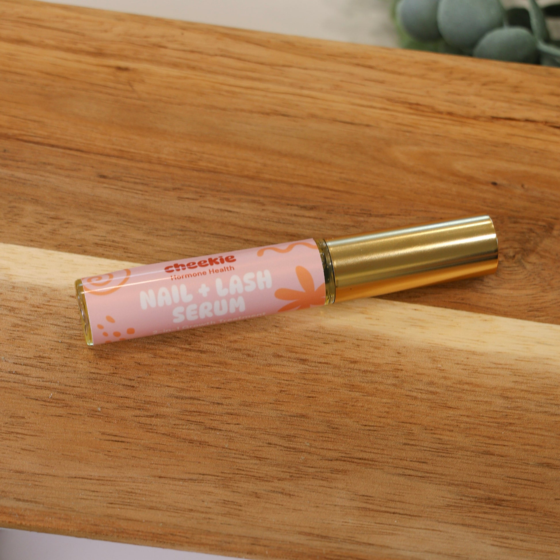 Lip balm tube with pink packaging on a wooden surface