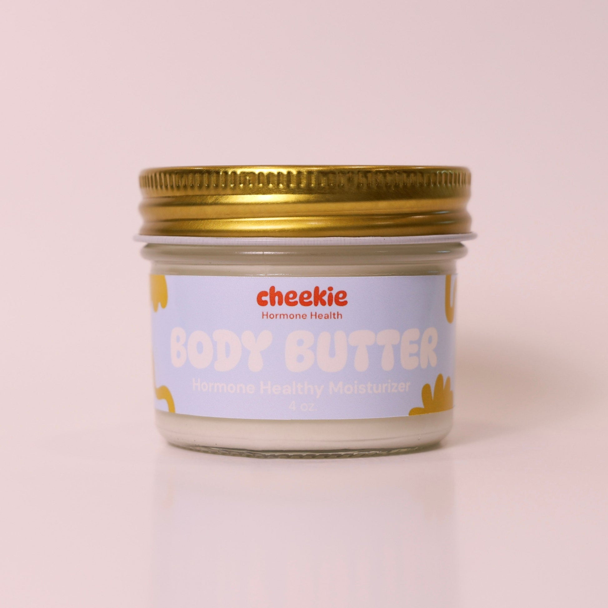 Jar of body butter with a gold lid on a light pink background