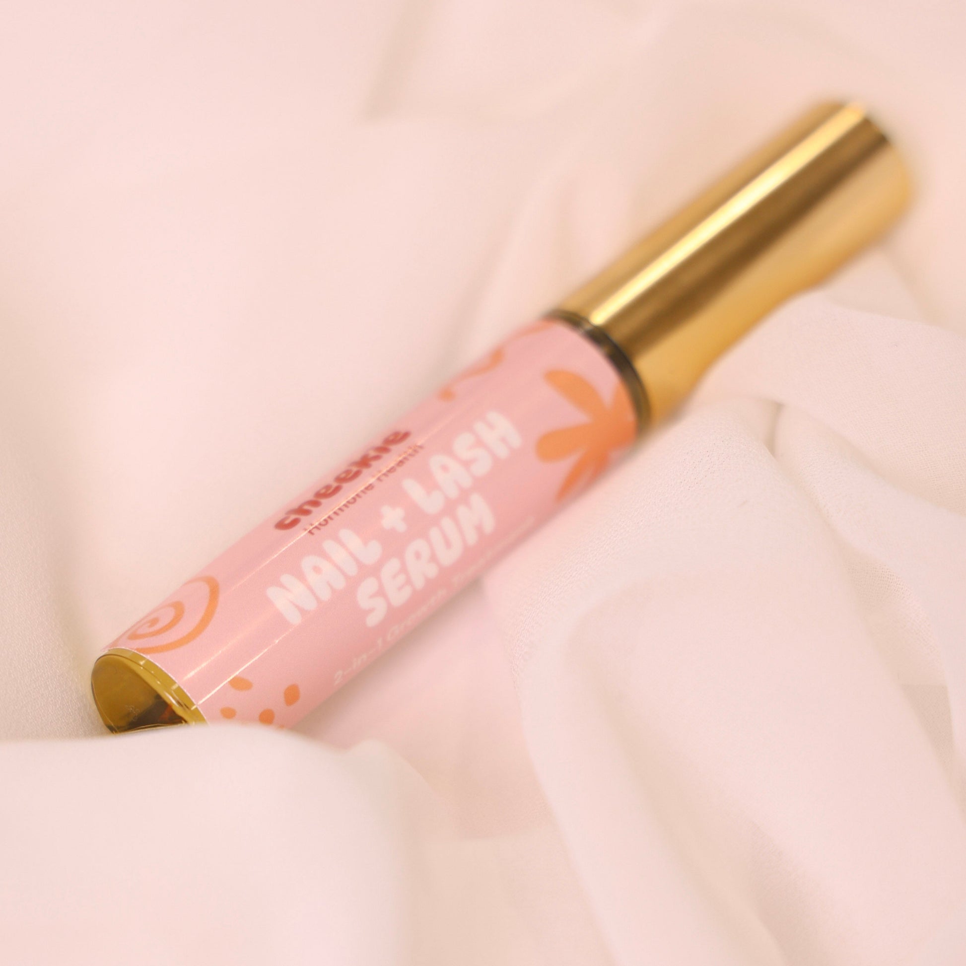 Pink serum bottle with gold cap on a soft pink background
