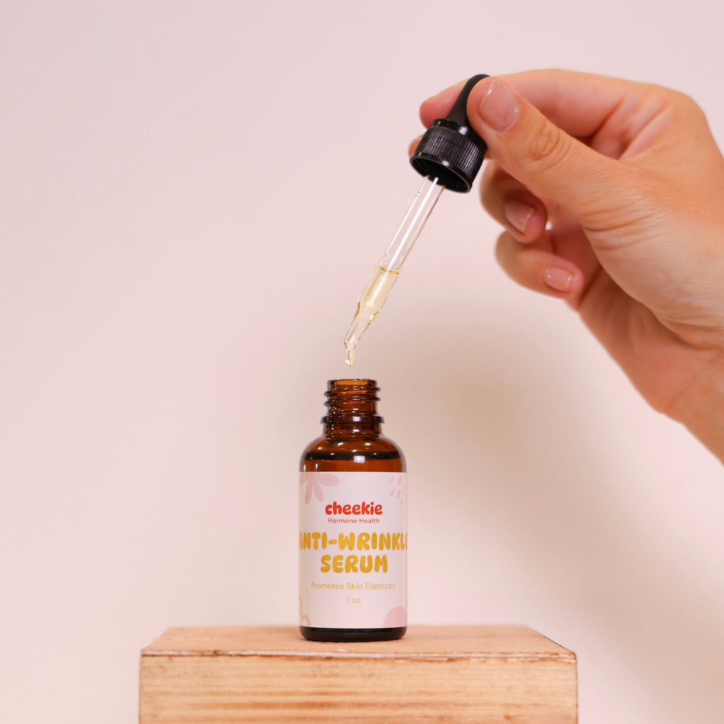 Hand holding a dropper over a bottle labeled 'chekic' on a wooden block with a plain background