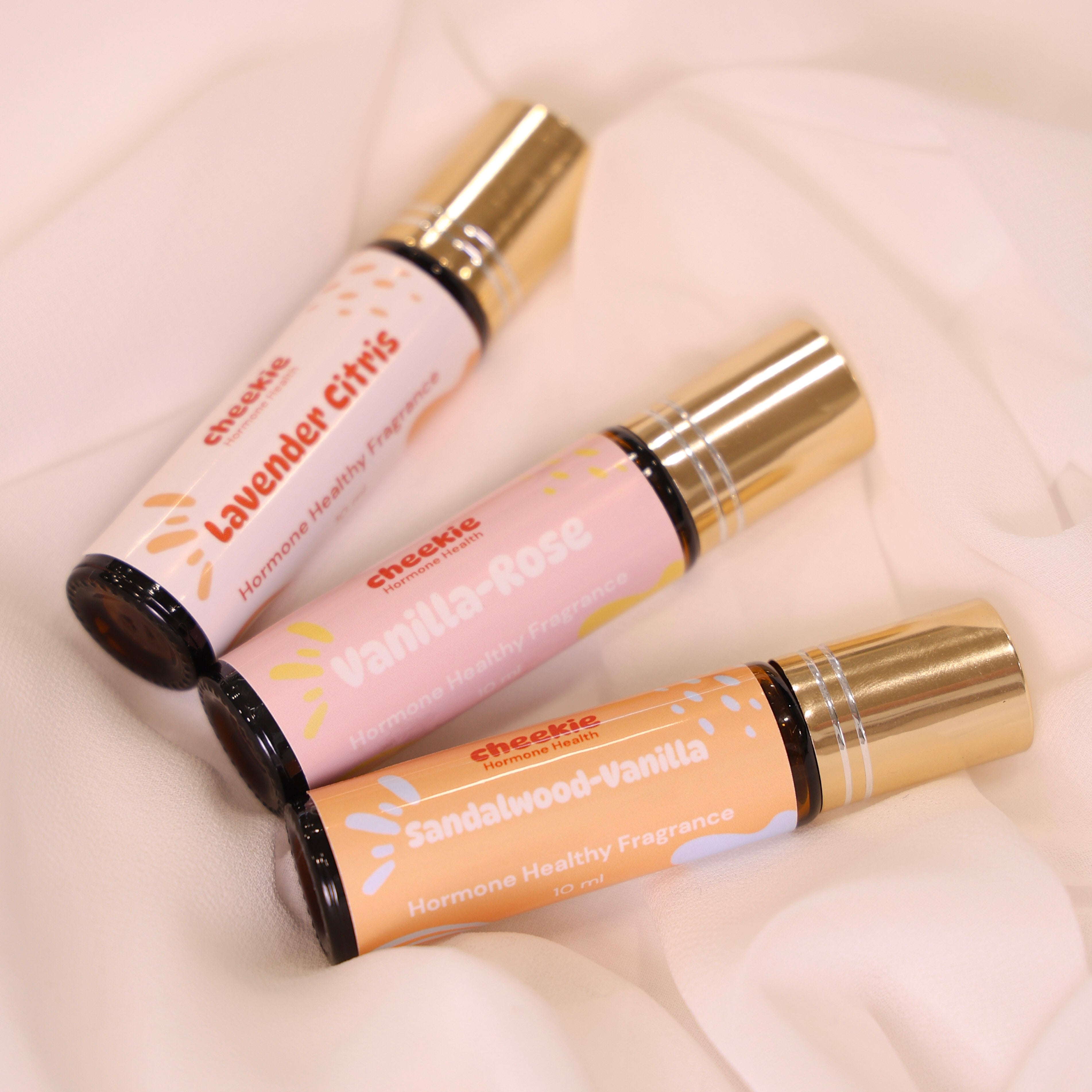 Three rollerball bottles of different scents on a soft white background